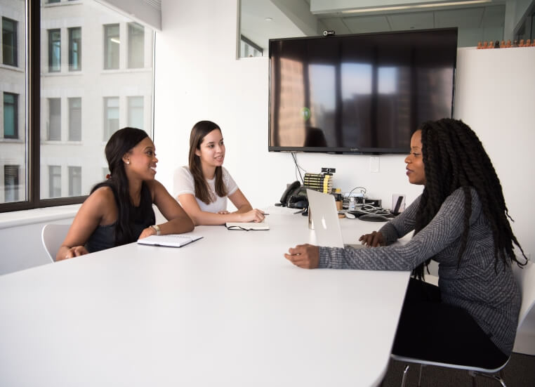 Two women sitting across an office desk from a human resources employee