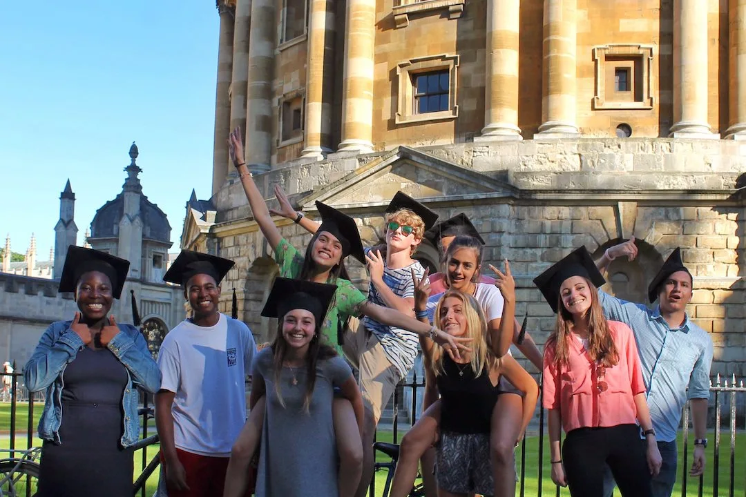 Group of Oxford Scholastica students wearing mortarboard graduation caps outside the Radcliffe Camera in Oxford