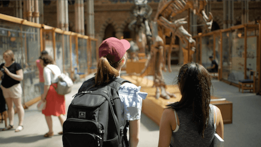 Two teen student girls looking at a dinosaur exhibit