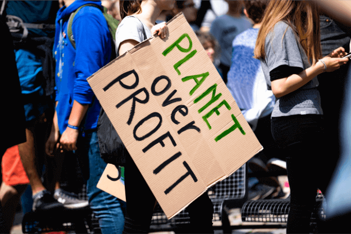 A student holding a sign that says "Planet Over Profit"