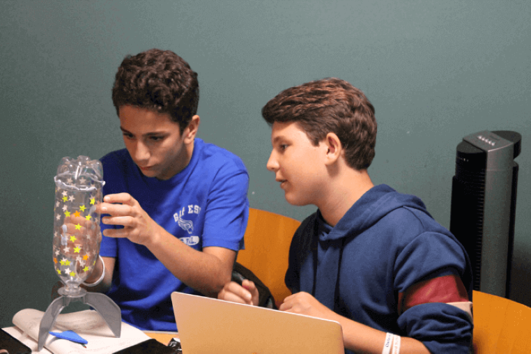 Two young engineering summer school students building a water bottle rocket