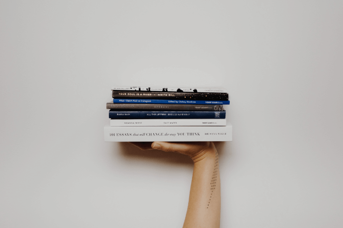 A student holding up books to learn how to write for a living