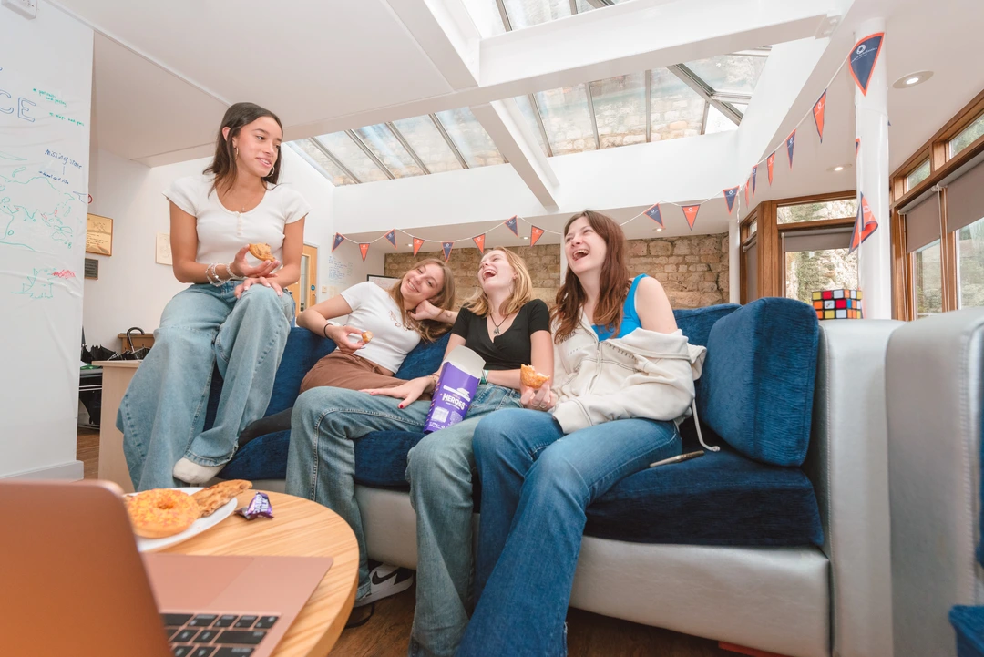 Four Oxford Scholastica students sitting on a sofa, laughing and relaxing