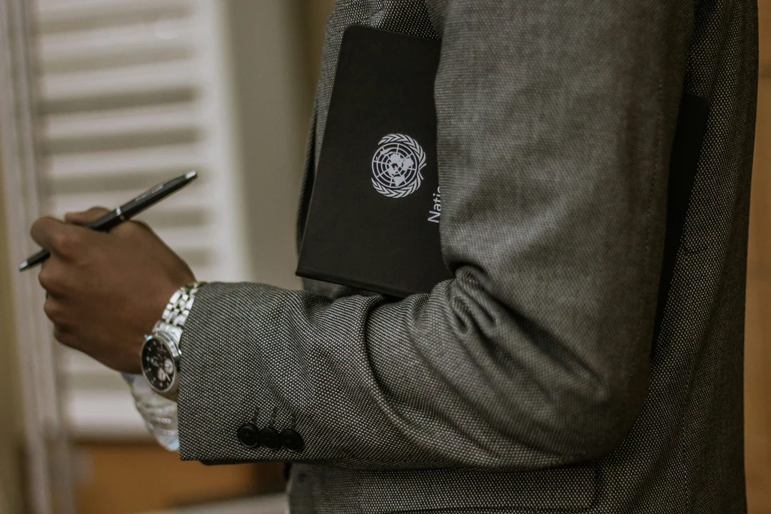 Man holding a black book with the UN logo on the front