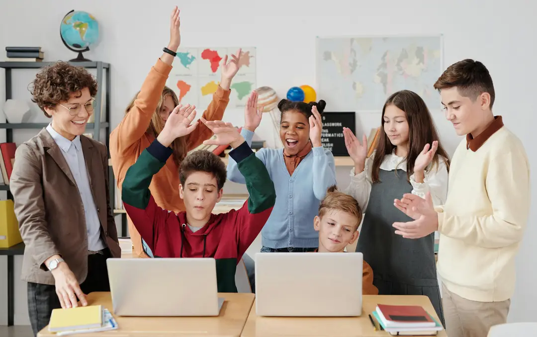 Group of children in a classroom, smiling and clapping