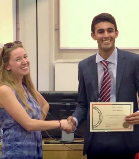 A tutor shaking a student hand during a Graduation at an Oxford Scholastica summer school.