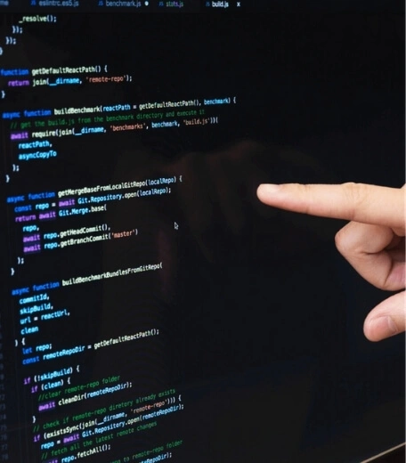 A person's finger pointing at some code on a screen