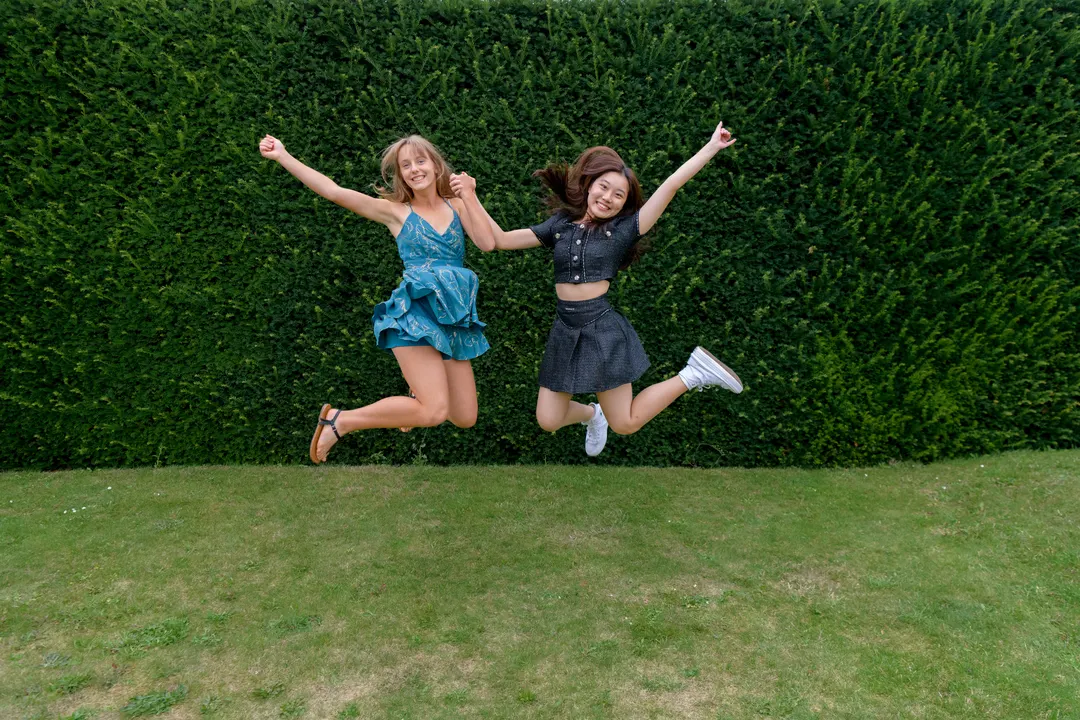 Two Oxford Scholastica students jumping in the air, posing