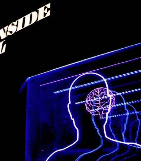 neon light display showing a person's outline and a diagram of their brain