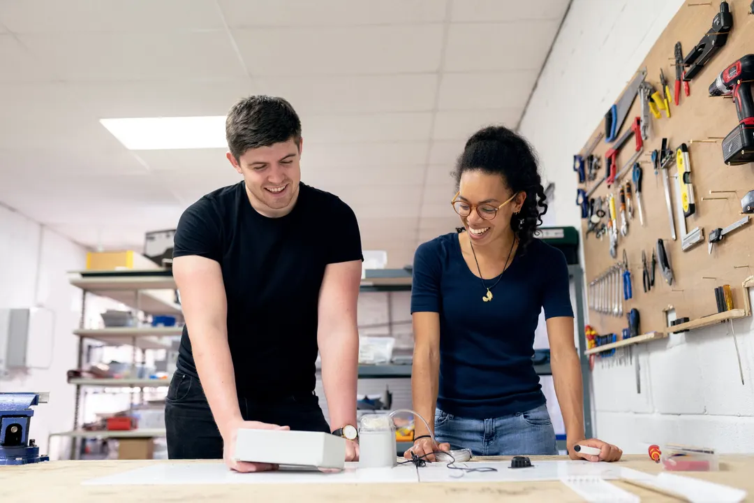 Two engineers leaning over a table, working on a project