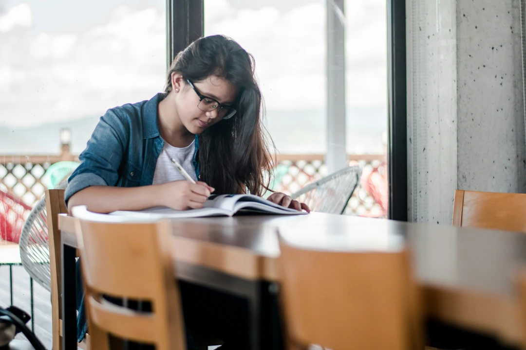 Student sitting at a desk writing in a notebook