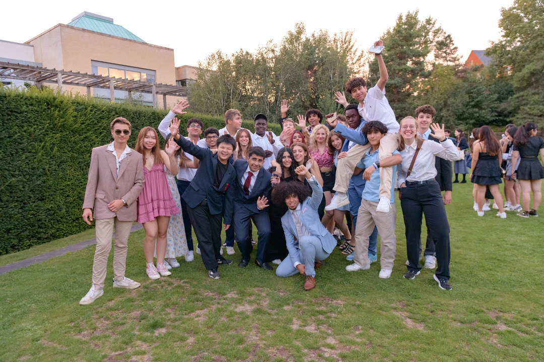 Group of teenagers posing for a photo. One student is sitting on another student's shoulders.