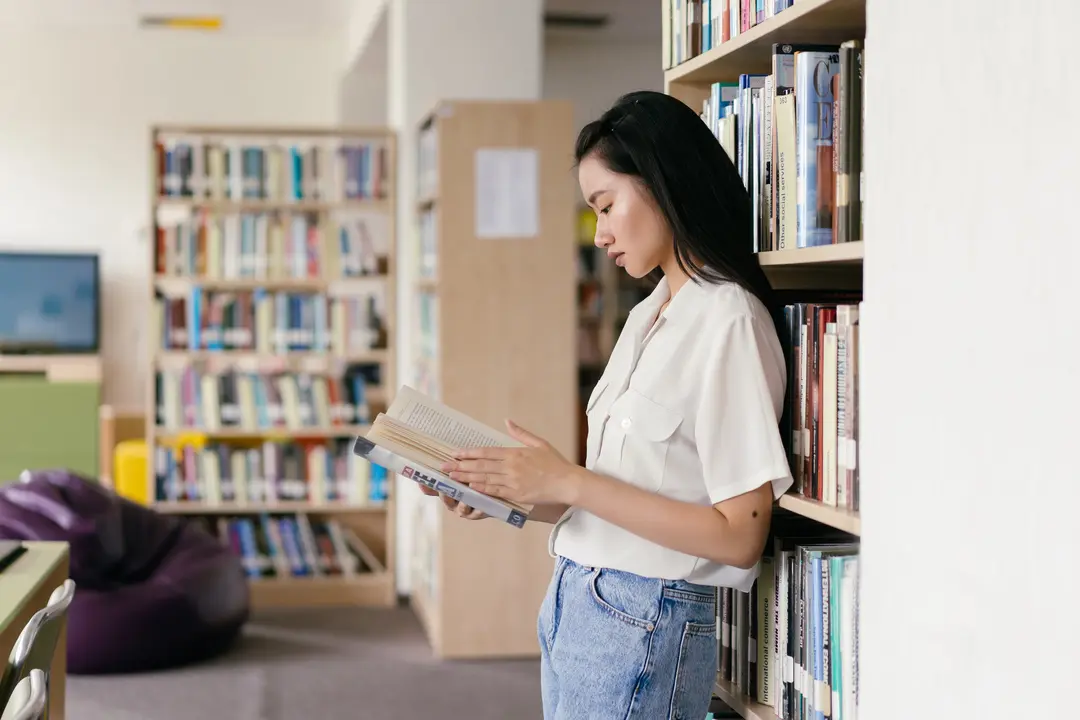 Student reading a book in a library