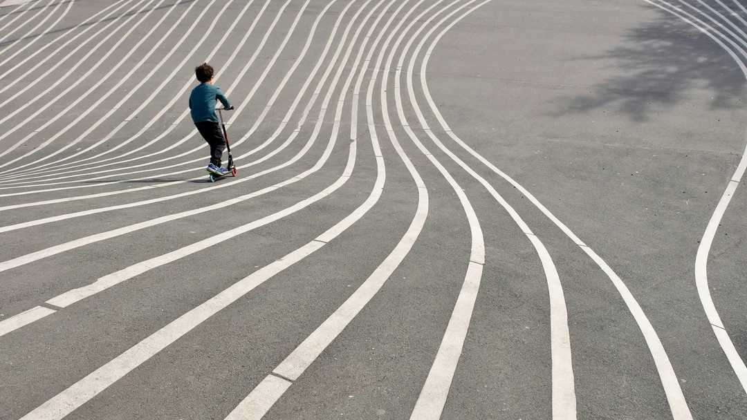 Child scooting down an urban playground designed by Bjarke Ingels Group