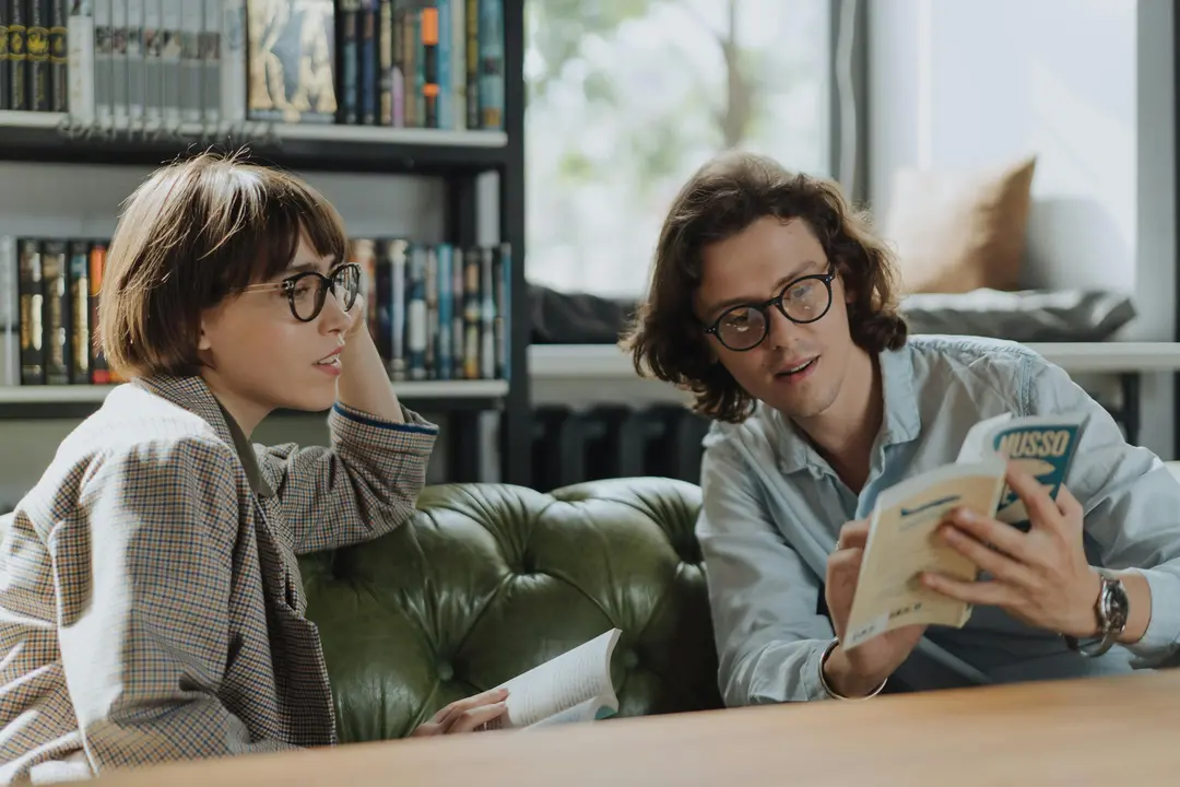 Two book club members sitting on a sofa, reading