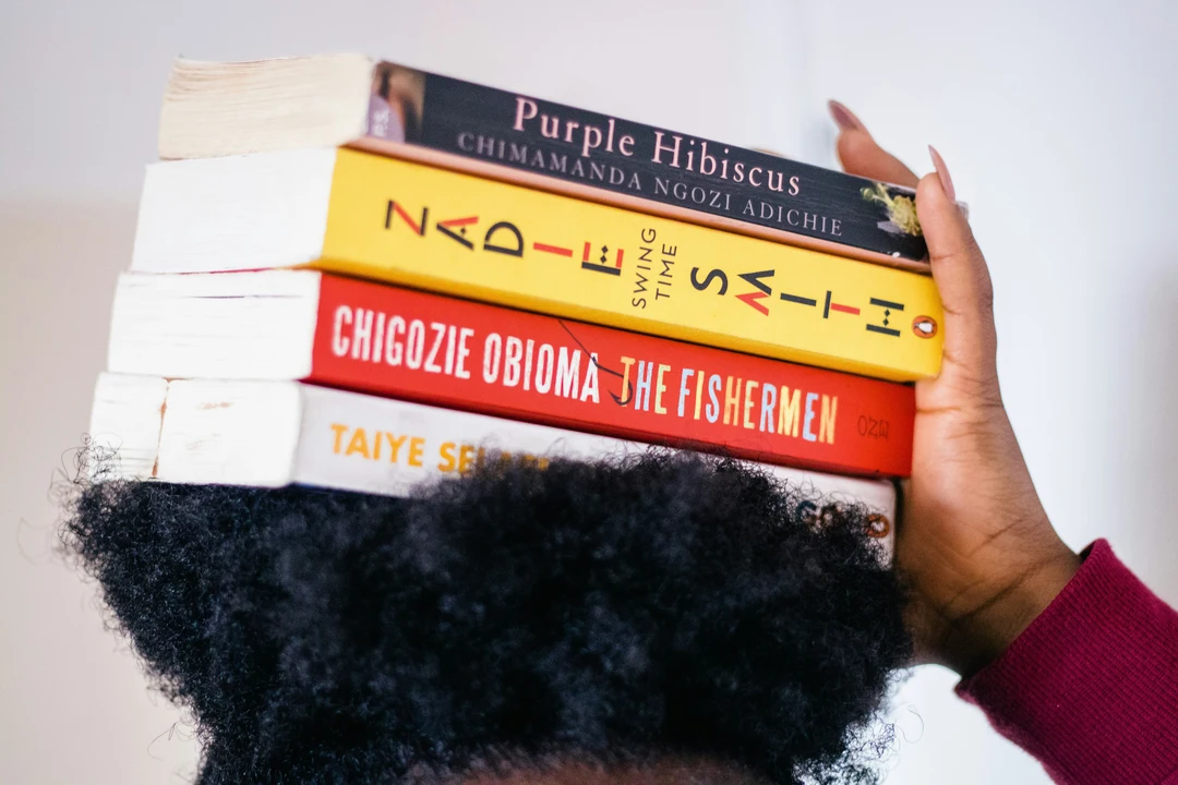 Four books stacked on top of a person's head
