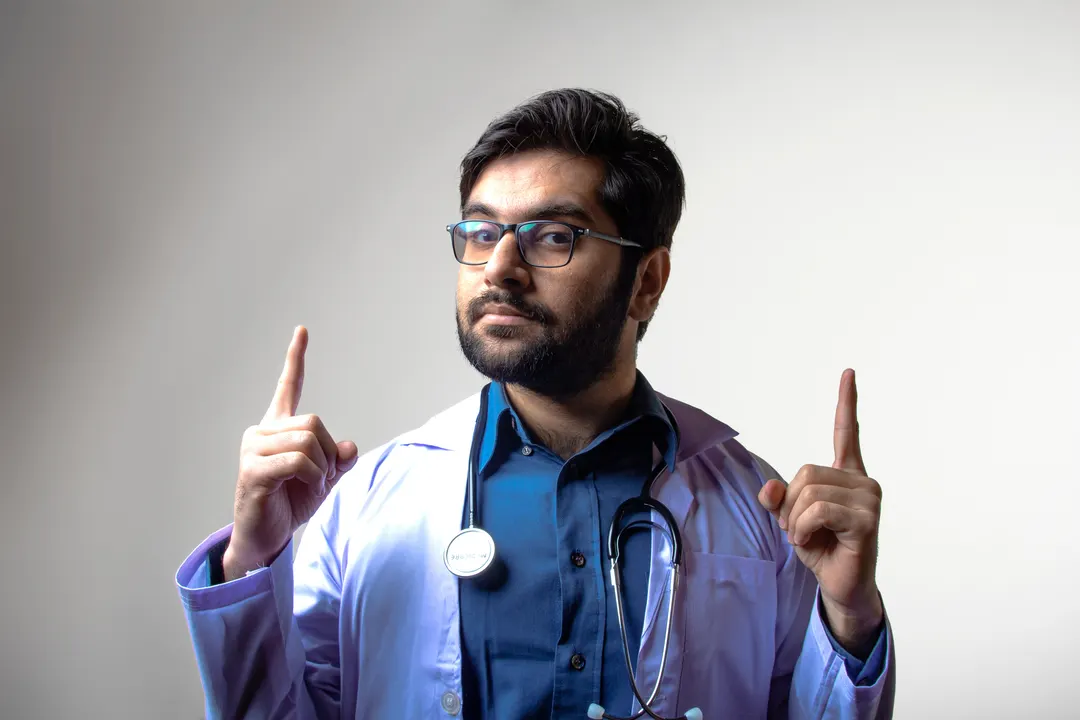 Doctor pointing upwards and looking at the camera