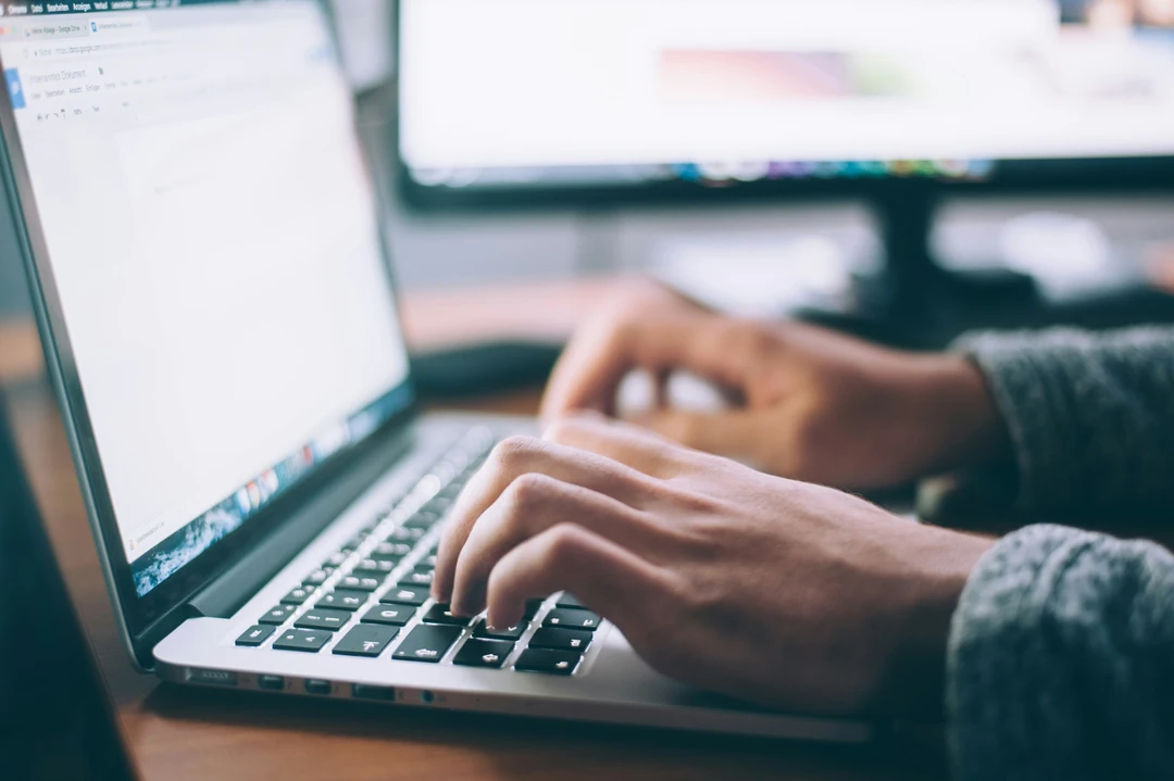 Close up of a pair of hands typing on a laptop