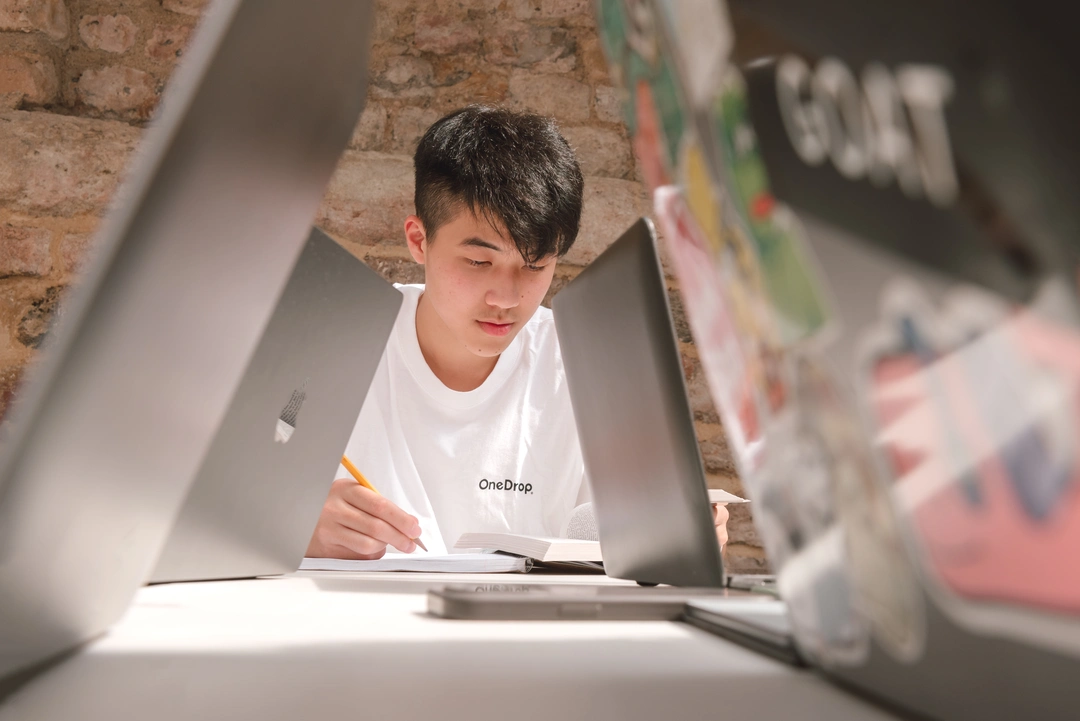 Student can be seen working through two rows of laptops