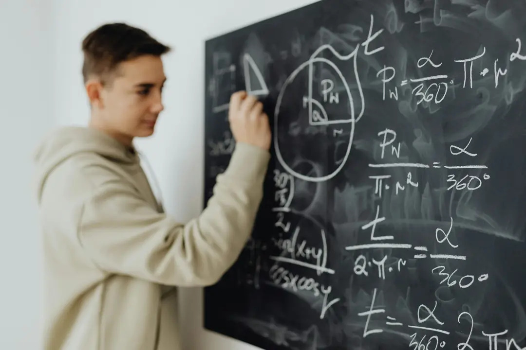 Student solving an equation on a chalkboard