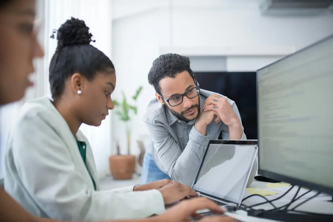 Intern typing on laptop, while mentor oversees