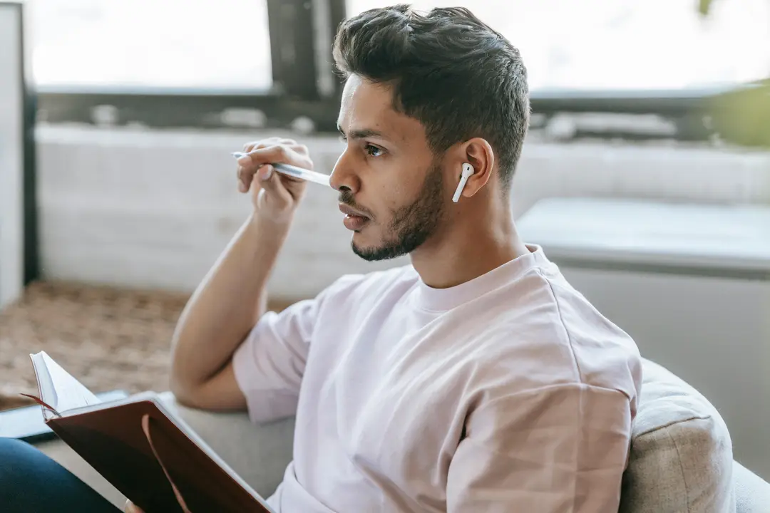 Man holding a notebook and pen, looking into the distance